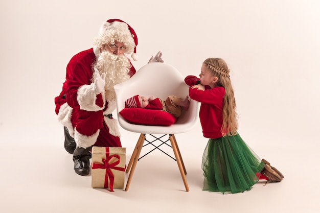 Papai Noel fantasiado de vermelho com uma menina e um bebê isolado no branco