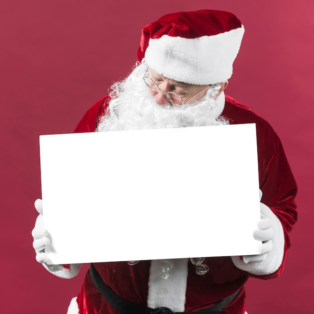 Papai Noel segurando papel branco em branco nas mãos