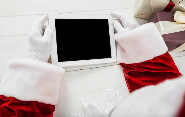 Foto grátis papai noel usando tablet na mesa