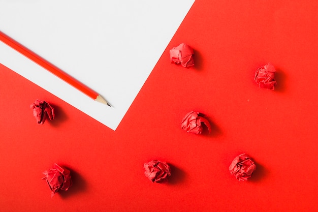Papel amassado vermelho sobre fundo de papel duplo com lápis