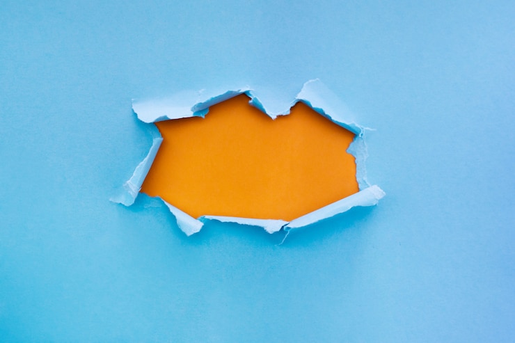 Foto grátis papel azul rasgado com fundo de cor laranja com espaço para texto