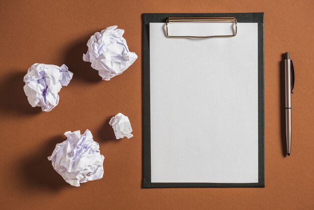 Papel colidido, caneta com papel em branco na prancheta contra um fundo colorido