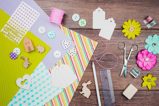 Papel colorido; botões; flores de papel; Tag; animais de recorte de madeira e papelaria na mesa de madeira