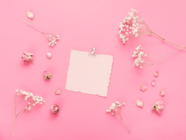 Papel em branco pequeno com ramos de flores na mesa