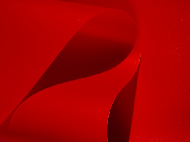 Papel monocromático curvado abstrato vermelho do close-up