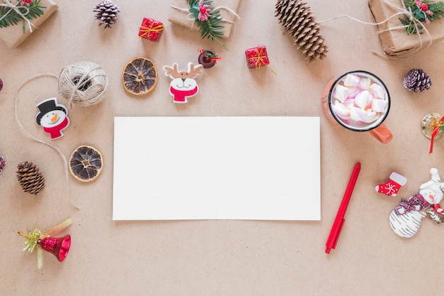 Papel perto de caneta, copo e decorações de natal