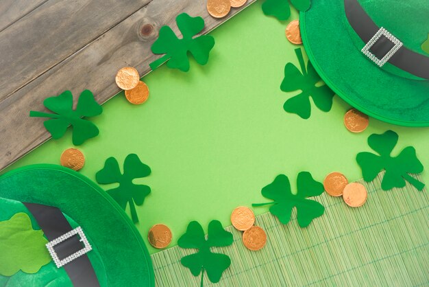 Papel perto de moedas, trevos decorativos e chapéu Saint Patricks