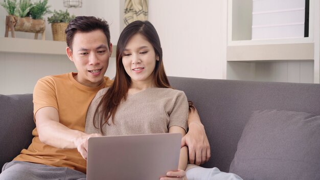 Par asiático, usando computador portátil, para, busca, teia, em, sala de estar, casa