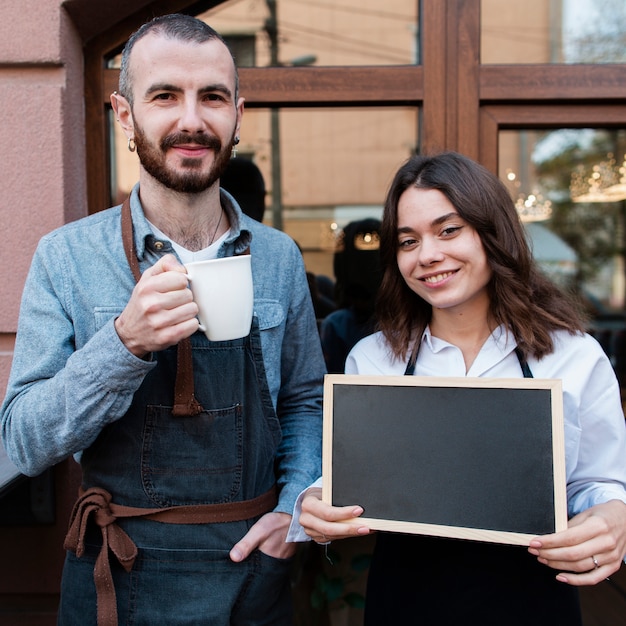 Par, café exterior, segurando, copo, e, quadro-negro