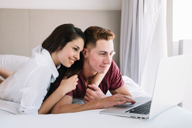 Par jovem, mentindo cama, com, laptop