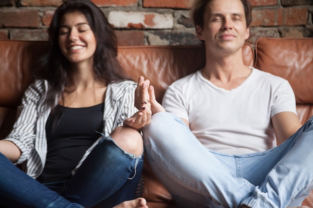 Par jovem, prática, ioga meditando, junto, casa, ligado, sofá