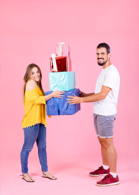 Par jovem, segurando, colorido, caixas presente, contra, cor-de-rosa, fundo