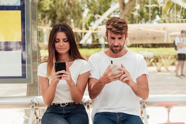 Par jovem, segurando, telefones celulares