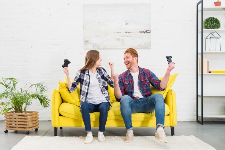 Foto grátis par jovem, sentando, ligado, amarela, sofá, em, a, sala de estar, alegrando, após, jogar, a, videogame