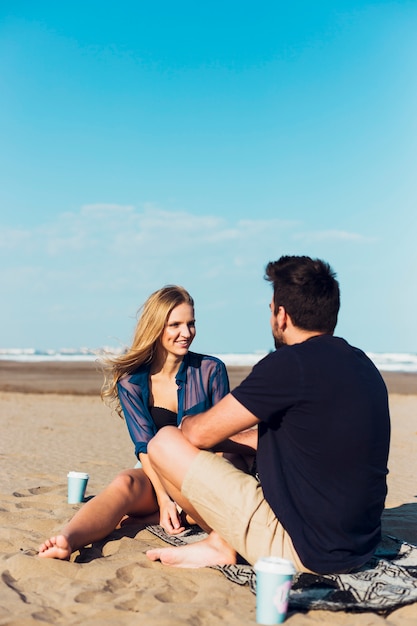 Par jovem, sentando praia