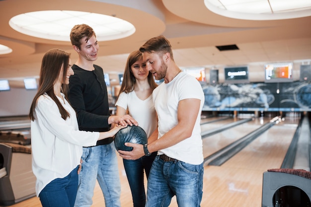 Para dar sorte. Jovens amigos alegres se divertem no clube de boliche nos fins de semana