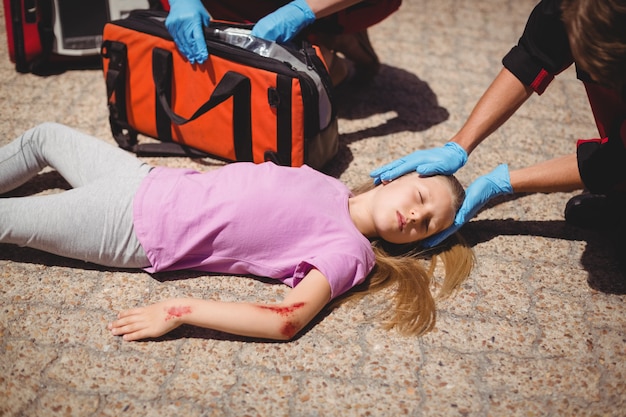 Paramédicos examinando garota ferida