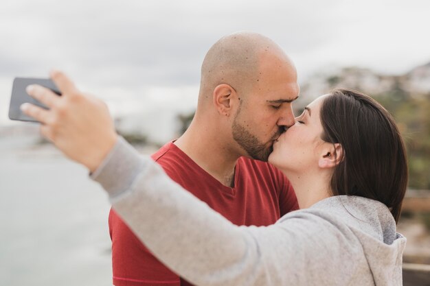 Parceiros se beijando enquanto tomava selfie