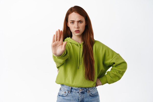 Pare a menina ruiva irritada estique a mão para proibir rejeitar e desaprovar recusar algo dizer que não proíba ação sobre fundo branco