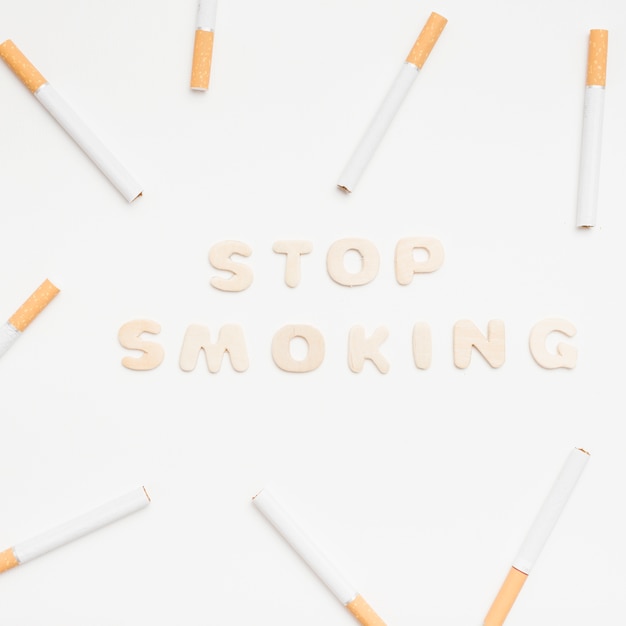 Pare de fumar texto rodeado por cigarros contra fundo branco