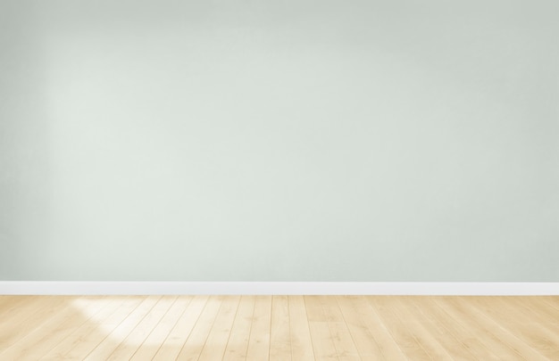 Parede verde clara em uma sala vazia com piso de madeira