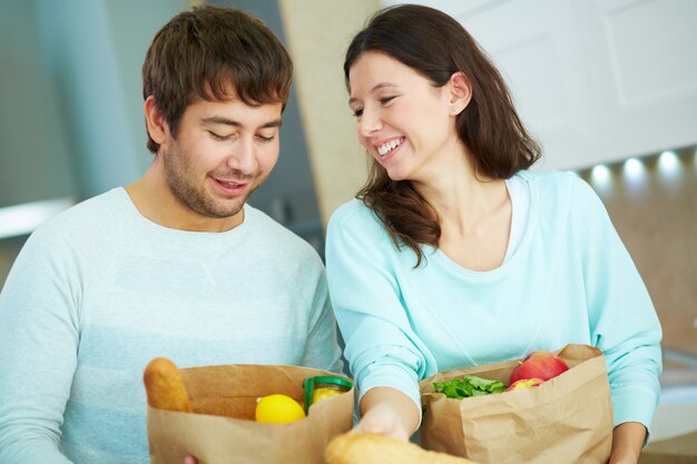 Pares felizes com sacos de papel cheios de comida