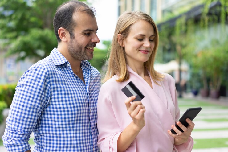 Foto grátis pares felizes que pagam pela compra usando o cartão e o telefone de crédito.
