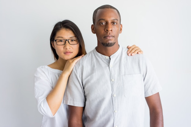 Pares inter-raciais novos bonitos calmos que olham a câmera.