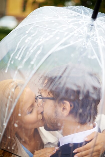Pares que beijam sob um guarda-chuva
