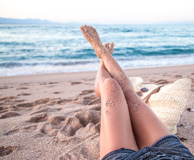 Parte do corpo. pés femininos na areia na praia à beira-mar fecham.