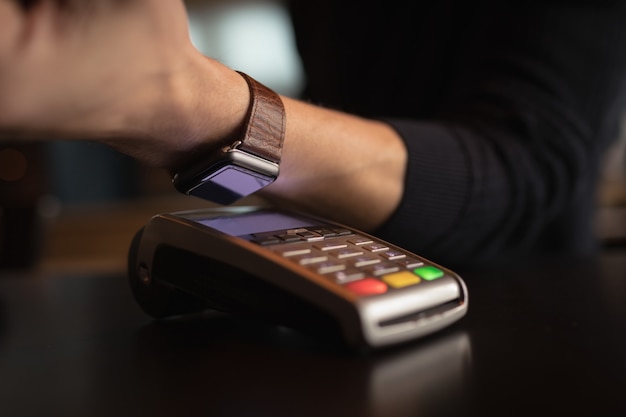 Foto grátis parte intermediária do homem fazendo pagamentos por meio de smartwatch