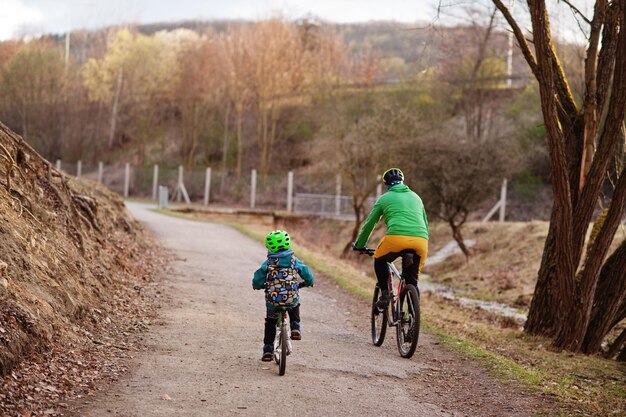 Parte traseira do pai com o filho andando de bicicleta no início da primavera