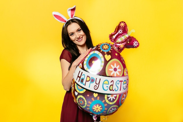Foto grátis páscoa. conceito de férias. mulher bonita usando orelhas de coelho, abraçando o balão de forma de ovo