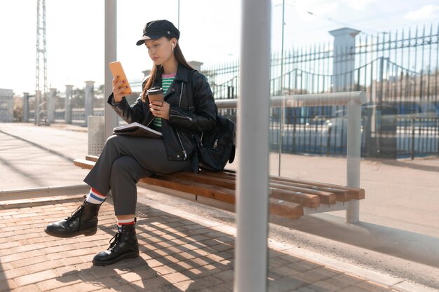 Passageiro sentado no banco da estação e usando telefone celular