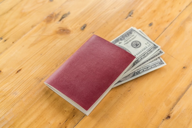 Passaporte em branco com dólares americanos em mesa de madeira.