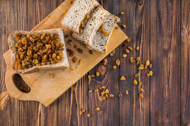 Passas no pão fatiado sobre a tábua de cortar na mesa