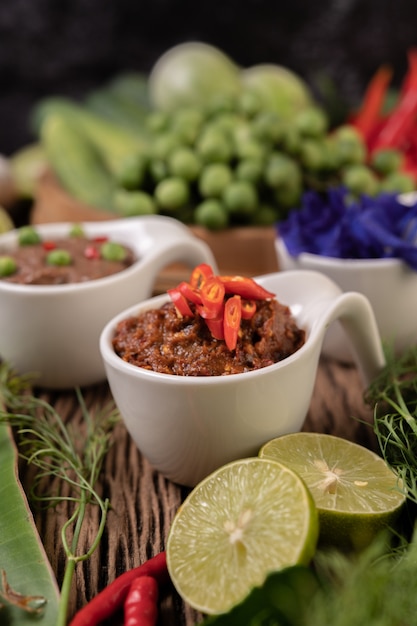 Pasta de chili de olhos vermelhos com limão e pimenta em piso de madeira.