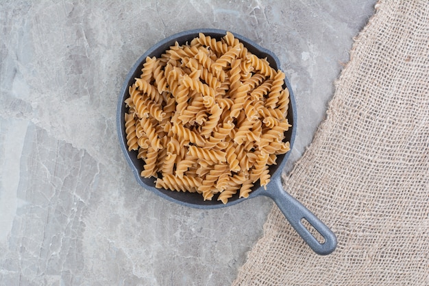 Foto grátis pasta espiral em uma panela de ferro sobre o mármore