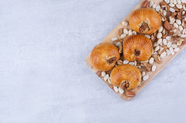 Pastelaria doce com miolo na placa de madeira com várias nozes.