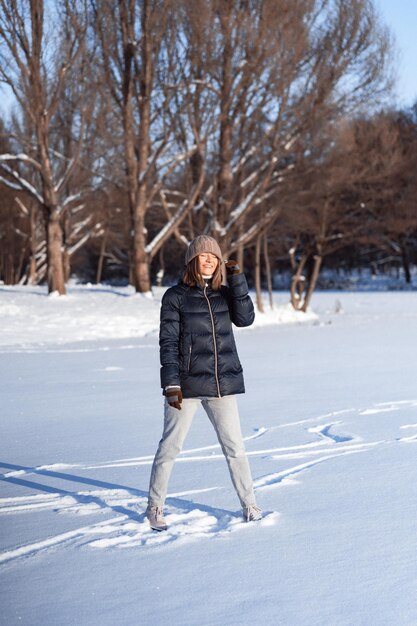 Patinação no gelo jovem, esportes de inverno, neve, diversão de inverno. Mulher aprendendo a patinar no lago, natureza, dia ensolarado.