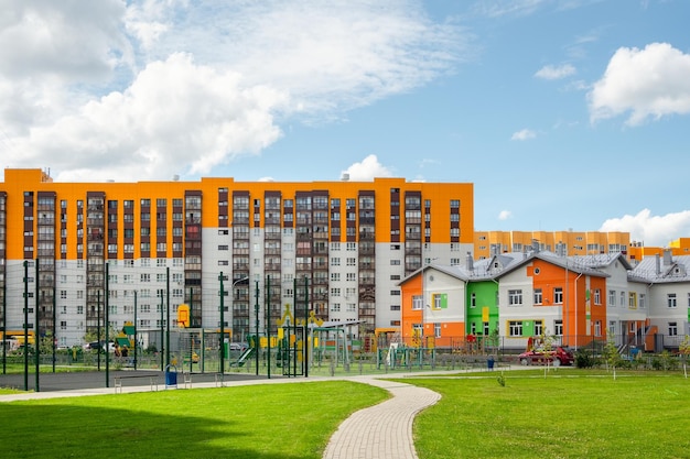 Pátio verde de um novo edifício moderno, um beco de azulejos através de um gramado verde parque infantil no pátio de uma nova área residencial