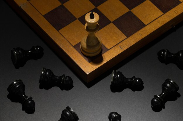 Peça de xadrez do rei branco com peças pretas caídas. conceito de sucesso