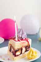 Foto grátis pedaço de bolo com vela e balões