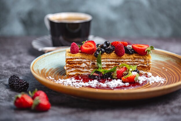 Pedaço de bolo de mel decorado com morango, groselha preta e framboesa