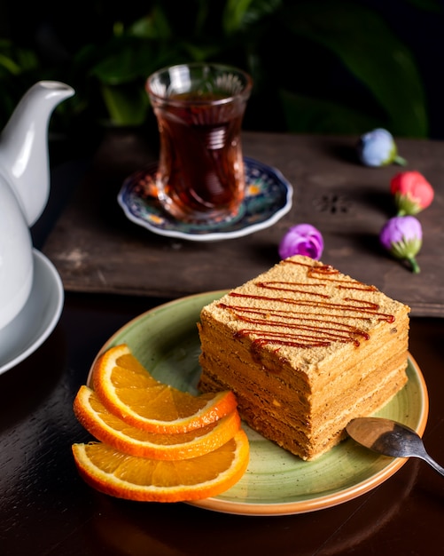 Pedaço de bolo servido com fatias de laranja, servido com chá 1