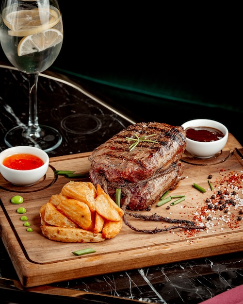 Pedaço de carne frita e batatas fritas com molhos