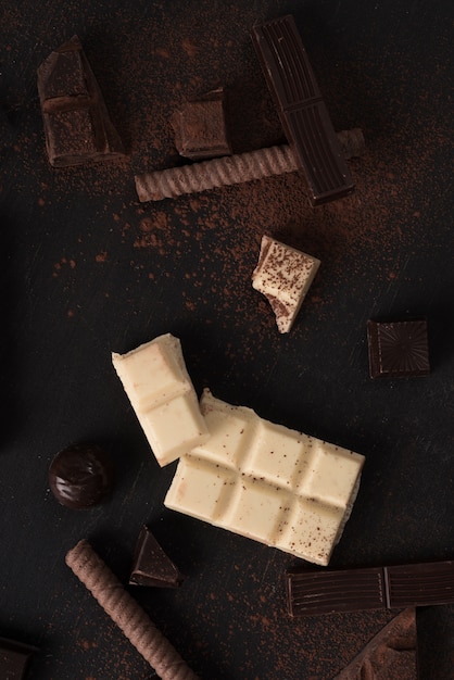 Foto grátis pedaços de barra de chocolate e doces sobre a superfície de madeira
