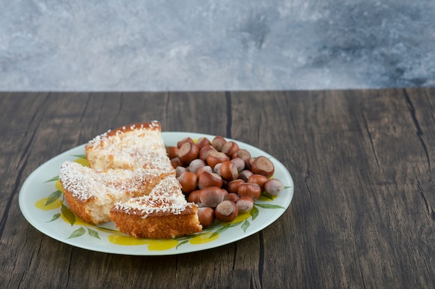 Pedaços de bolo delicioso com nozes de macadâmia colocados sobre uma mesa de madeira