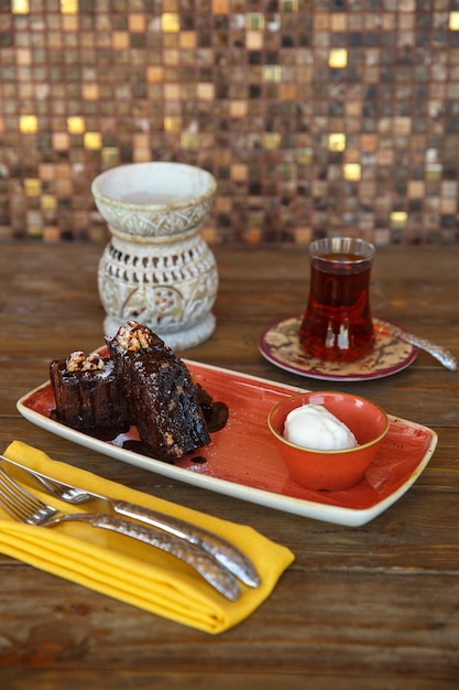 Pedaços de brownie com sorvete de baunilha, servidos com chá preto