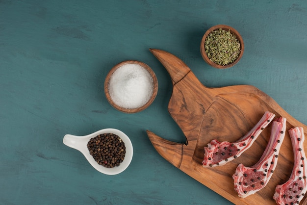 Pedaços de carne crua na placa de madeira com sal e especiarias.